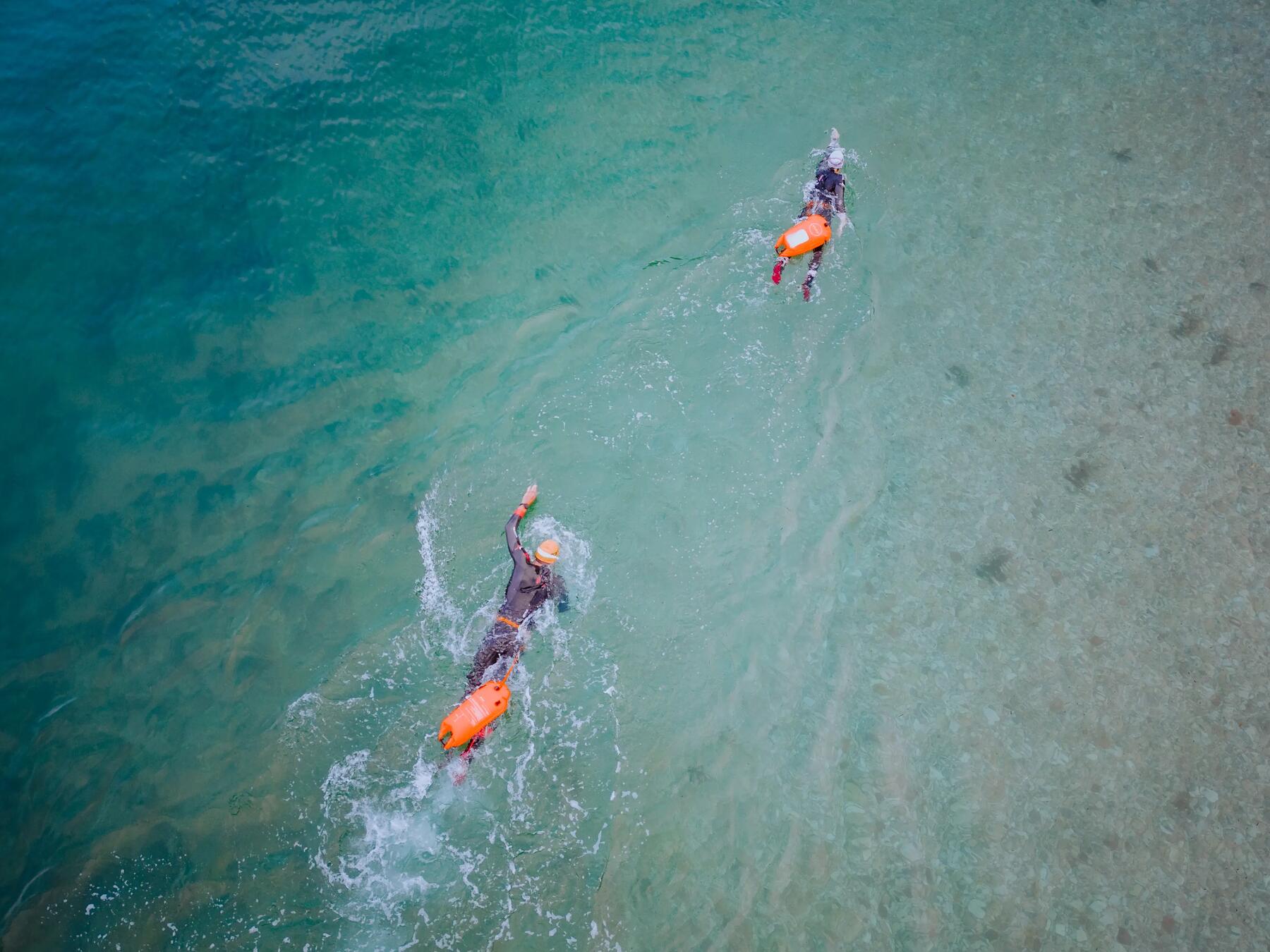 Dwóch pływaków pływających z bojkami w piankach open water