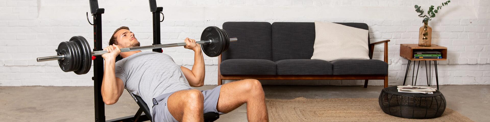 Mężczyzna w odzieży fitness wykonujący ćwiczenia na klatkę piersiową ze sztangą