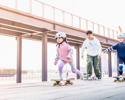 Teenager, younger boy and young girl skateboarding