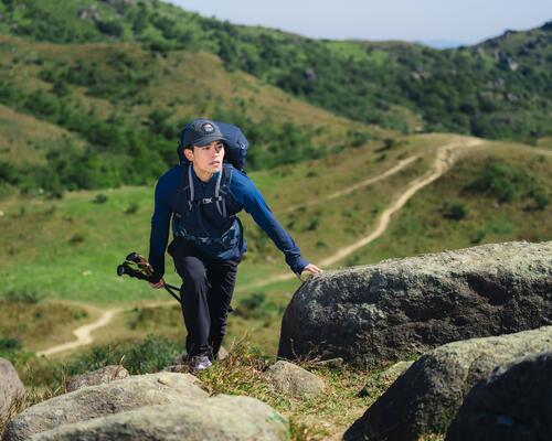 mężczyzna z plecakiem na plecach i kijkami trekkingowymi w rękach wędrujący po górach