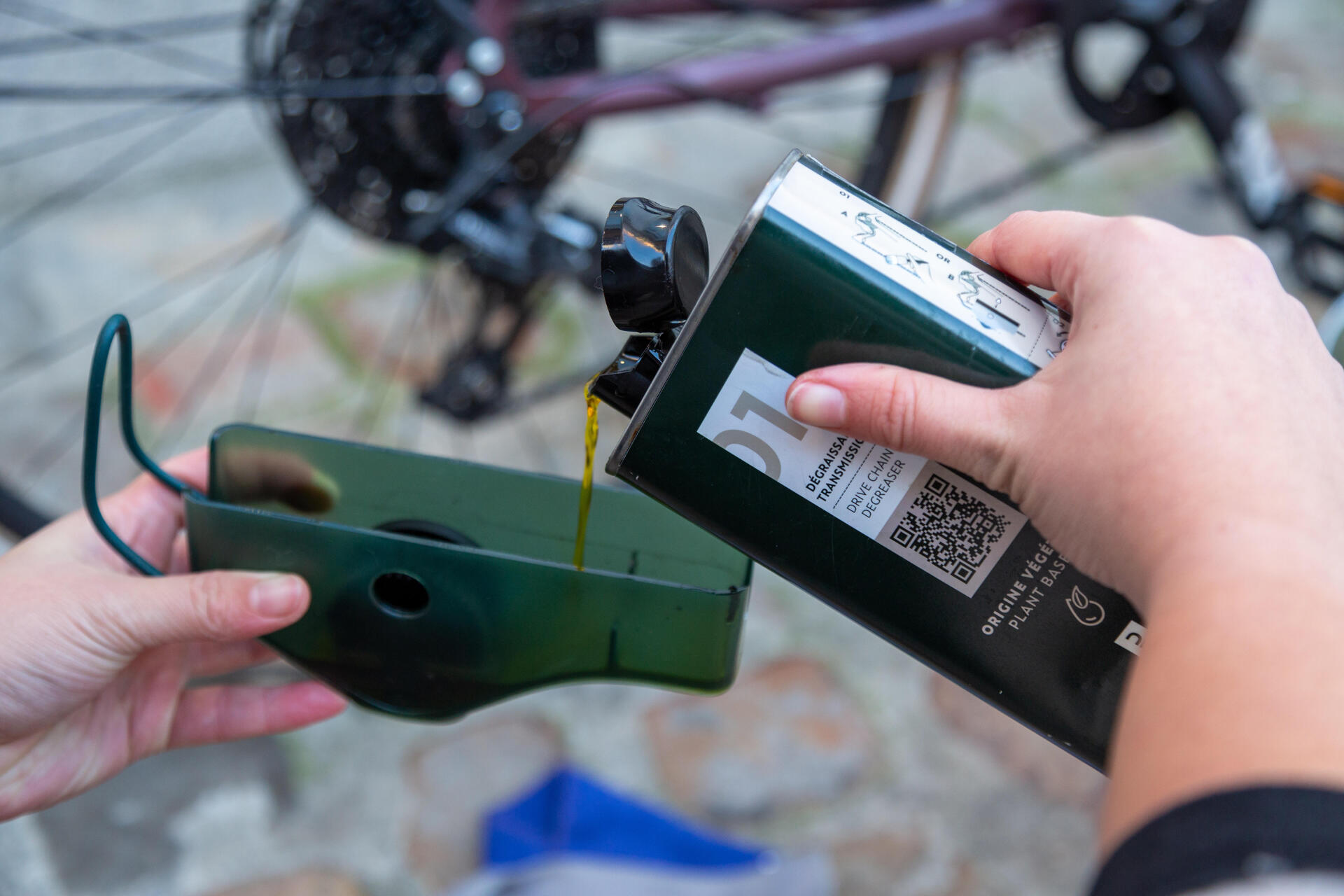 Someone pouring drivetrain cleaner in to a bike chain cleaning tool.