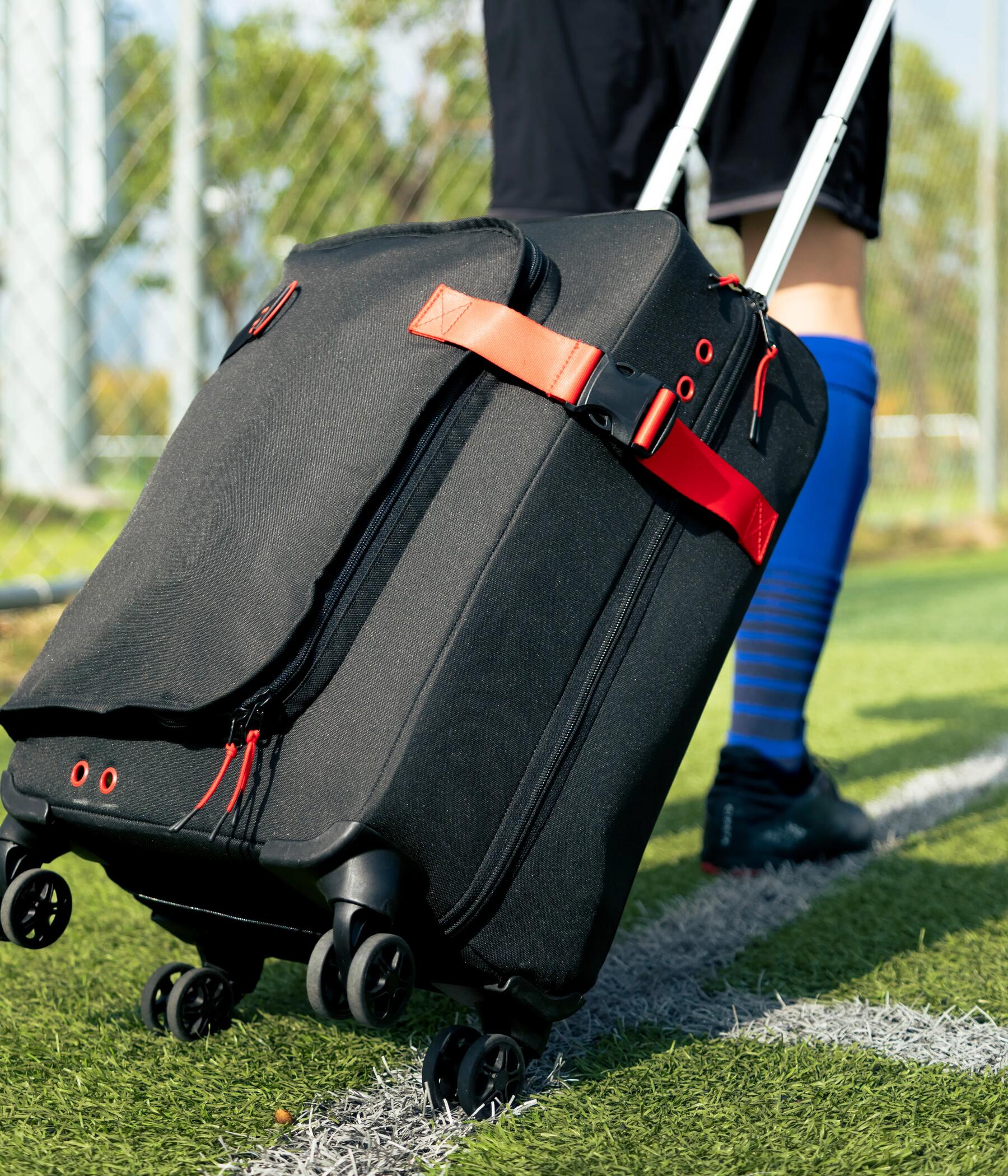 Person pulling a kipsta suitcase on the grass of a football court