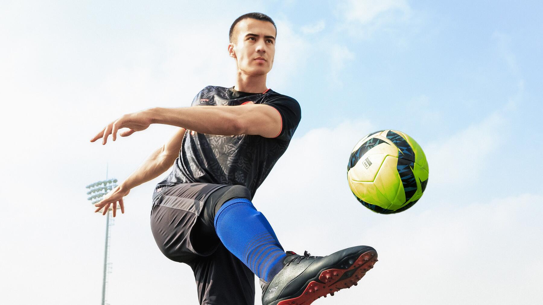 Mann schießt Ball aus der Luft. Blauer Himmel im Hintergrund.