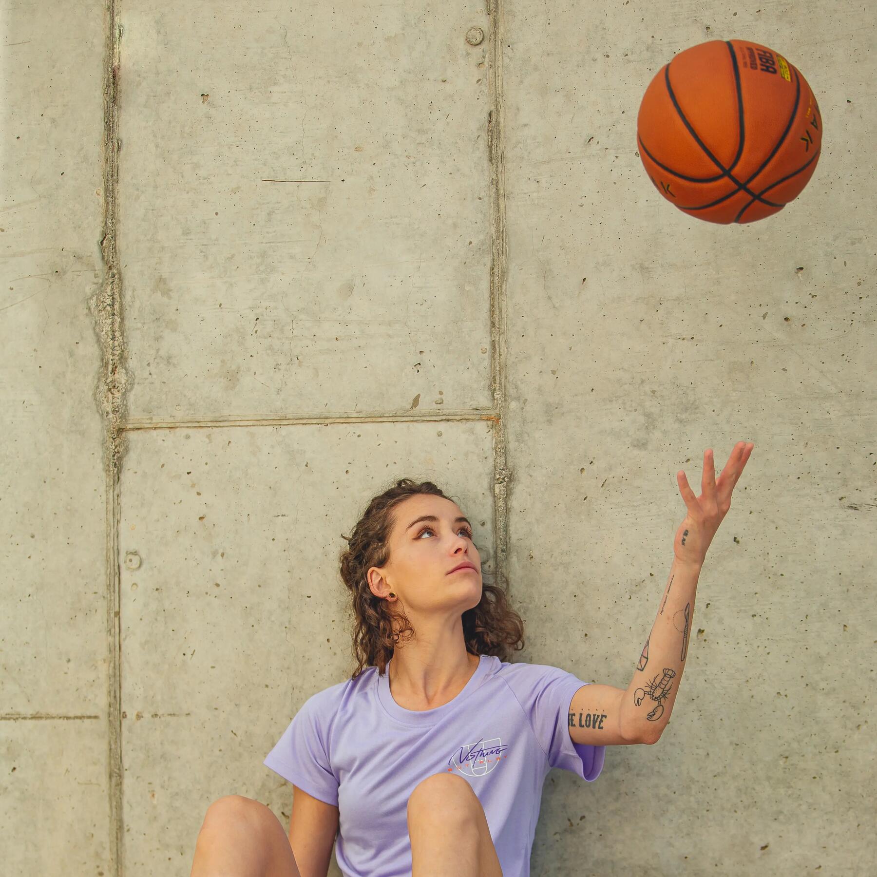 Woman throwing basketball in the air while seated