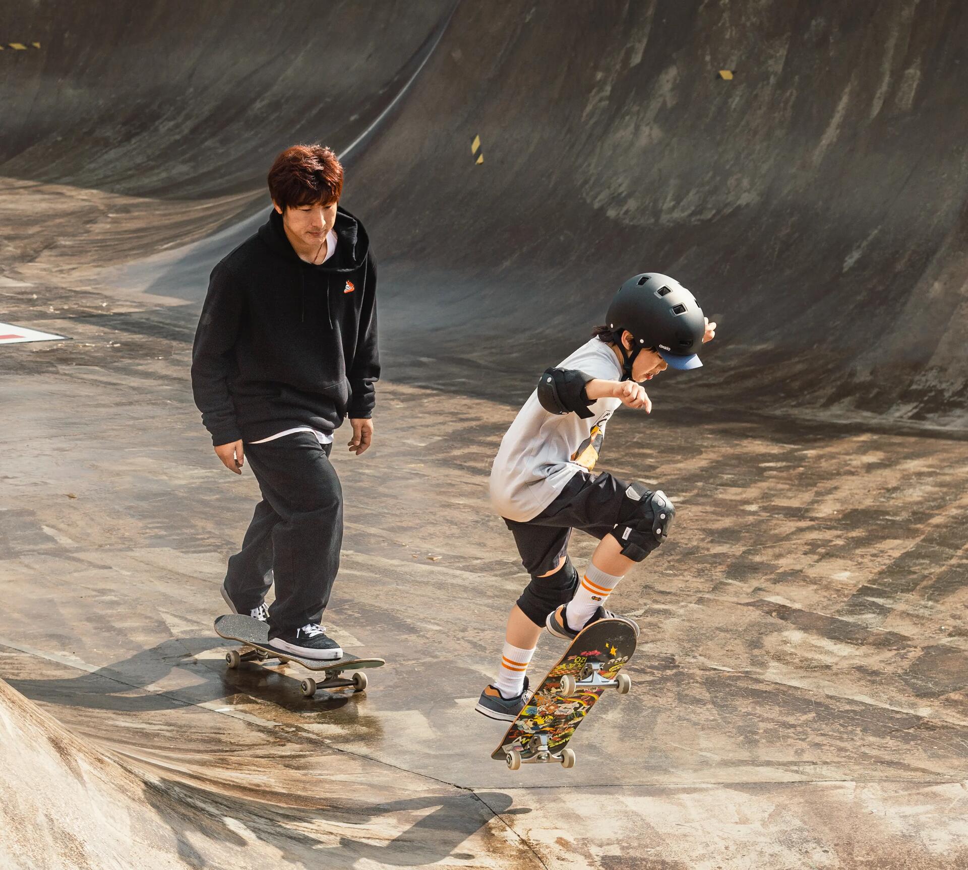 Teenager and young boy doing tricks at a skate park