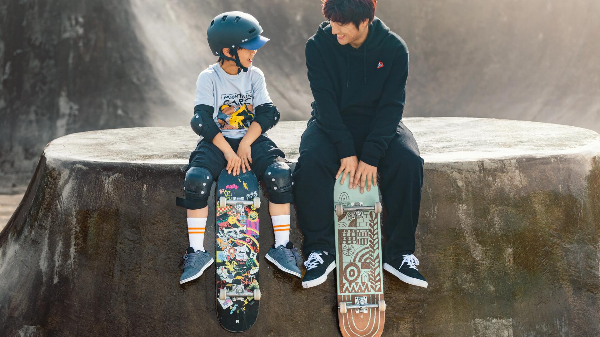 Mężczyzna i chłopiec siedzący z deskorolkami na skateparku