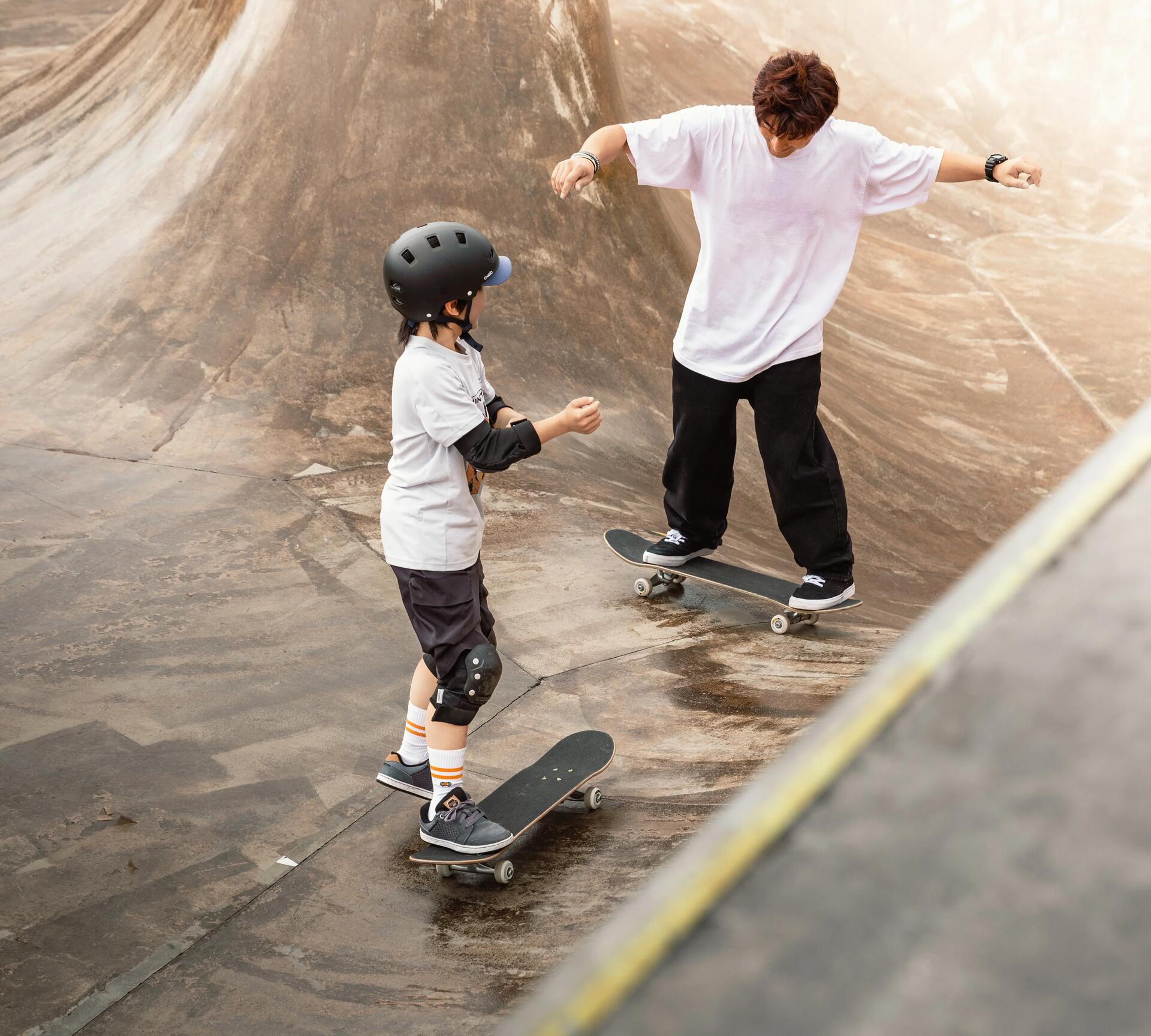 Teenager and young boy practising at a skate park