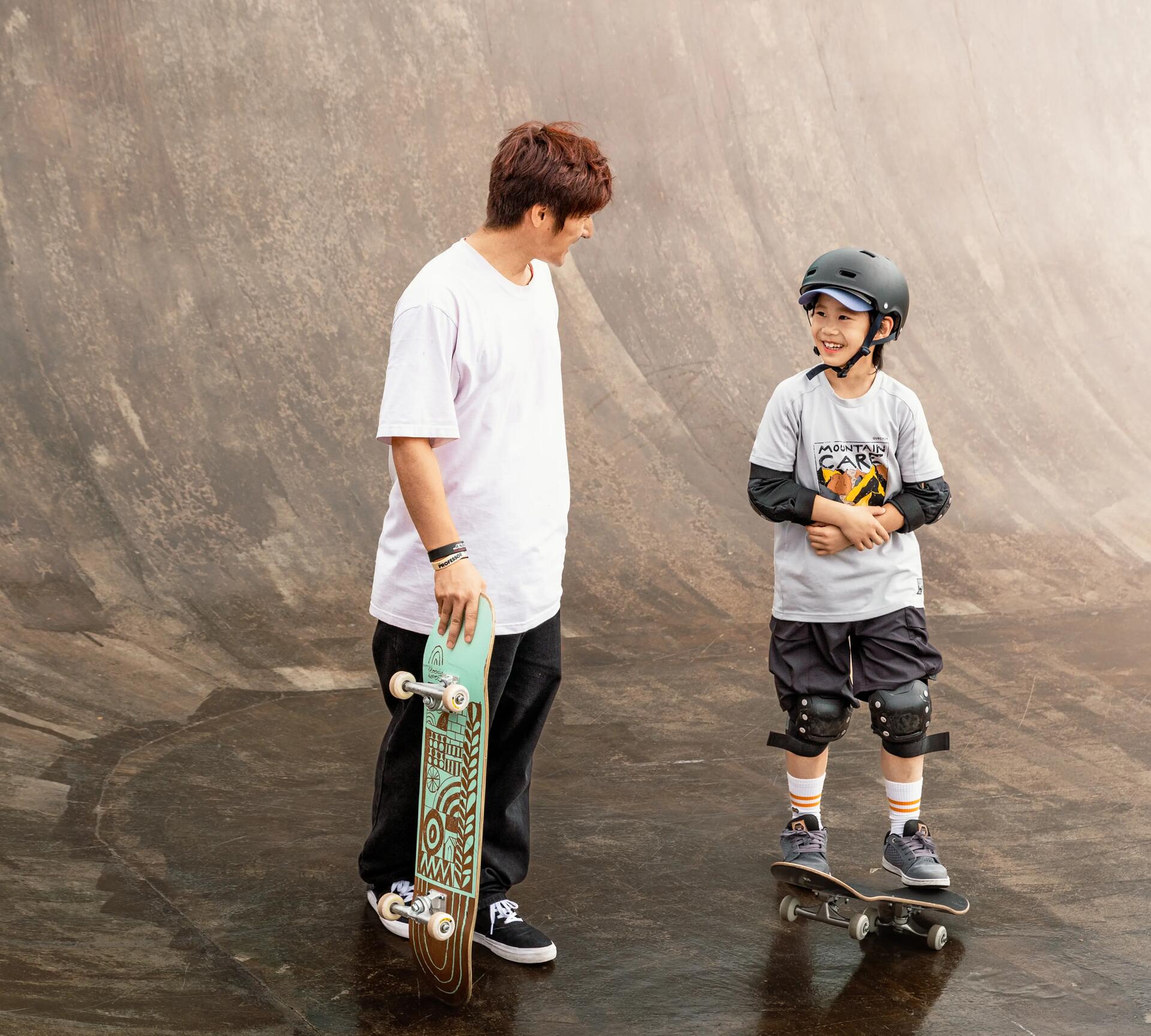 Teenager and younger boy hanging out with their skateboards on a skate ramp