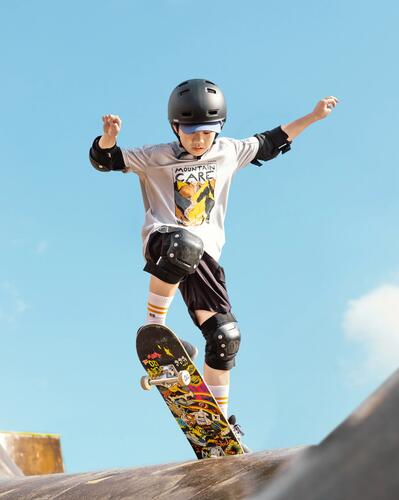 Chlapec s prilbou a chráničmi na skateboarde
