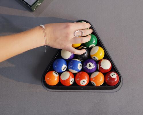 mężczyzna trzymający kij snookerowy opierając się o stół do gry w snookera