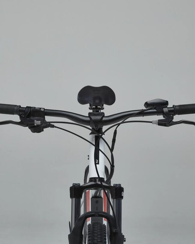 Schwarzer Fahrradlenker mit grauen Griffen und Bremsschaltern, Fahrradrahmen in Weiß und Schwarz, grauer neutraler Hintergrund.