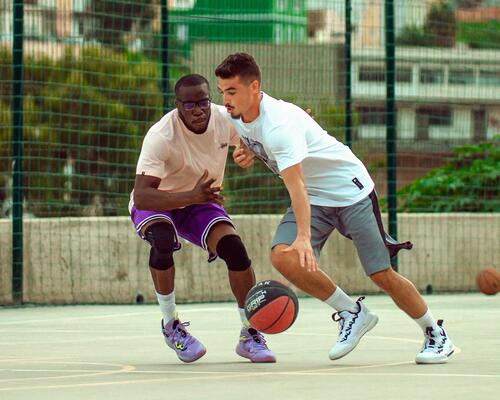 Two men playing basketball and dribbling