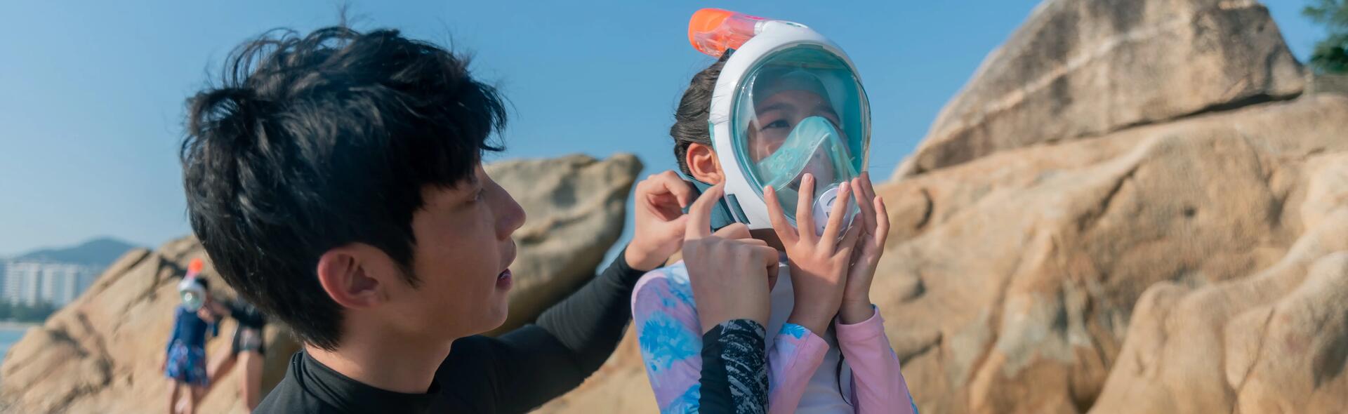 chłopiec zakładający dziewczynce maskę do snorkelinguu
