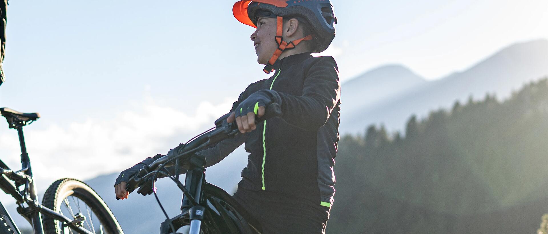 chłopiec w kasku rowerowym stojący na rowerze górskim