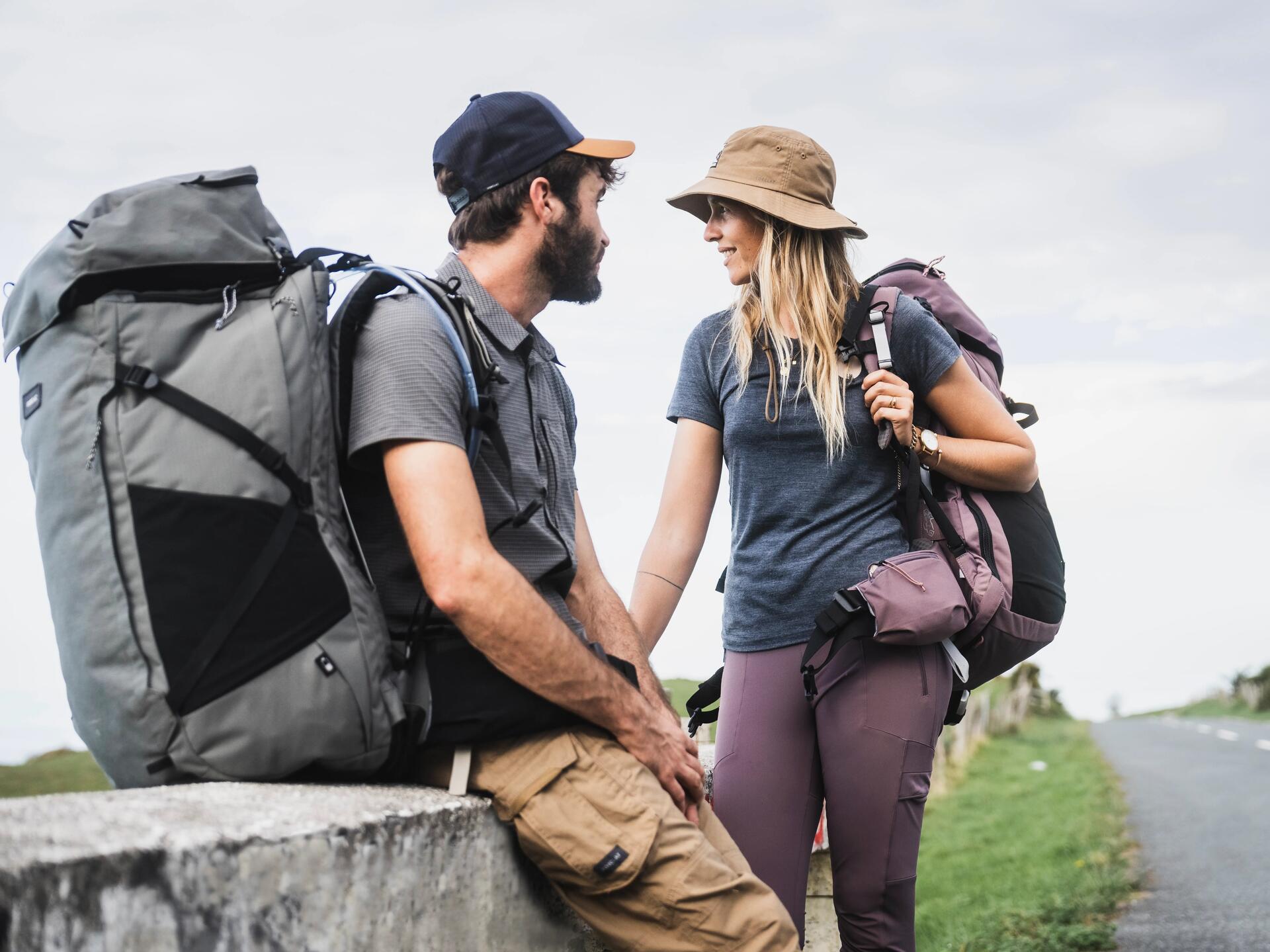 Kobieta i mężczyzna w odzieży trekkingowej stojący na szlaku z plecakami turystycznymi na plecach
