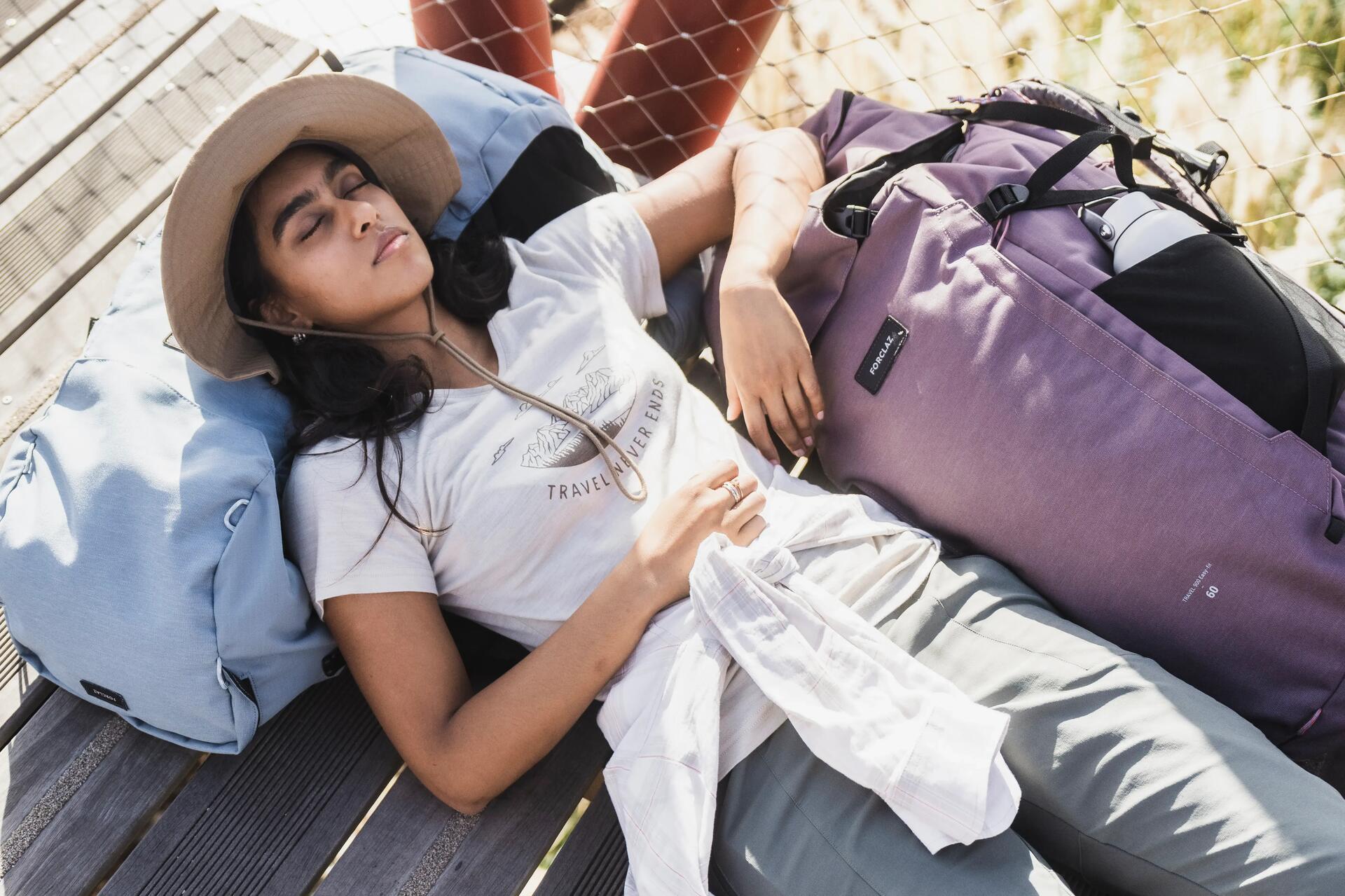 kobieta w odzieży turystycznej leżąca na spakowanych torbach podróżnych 