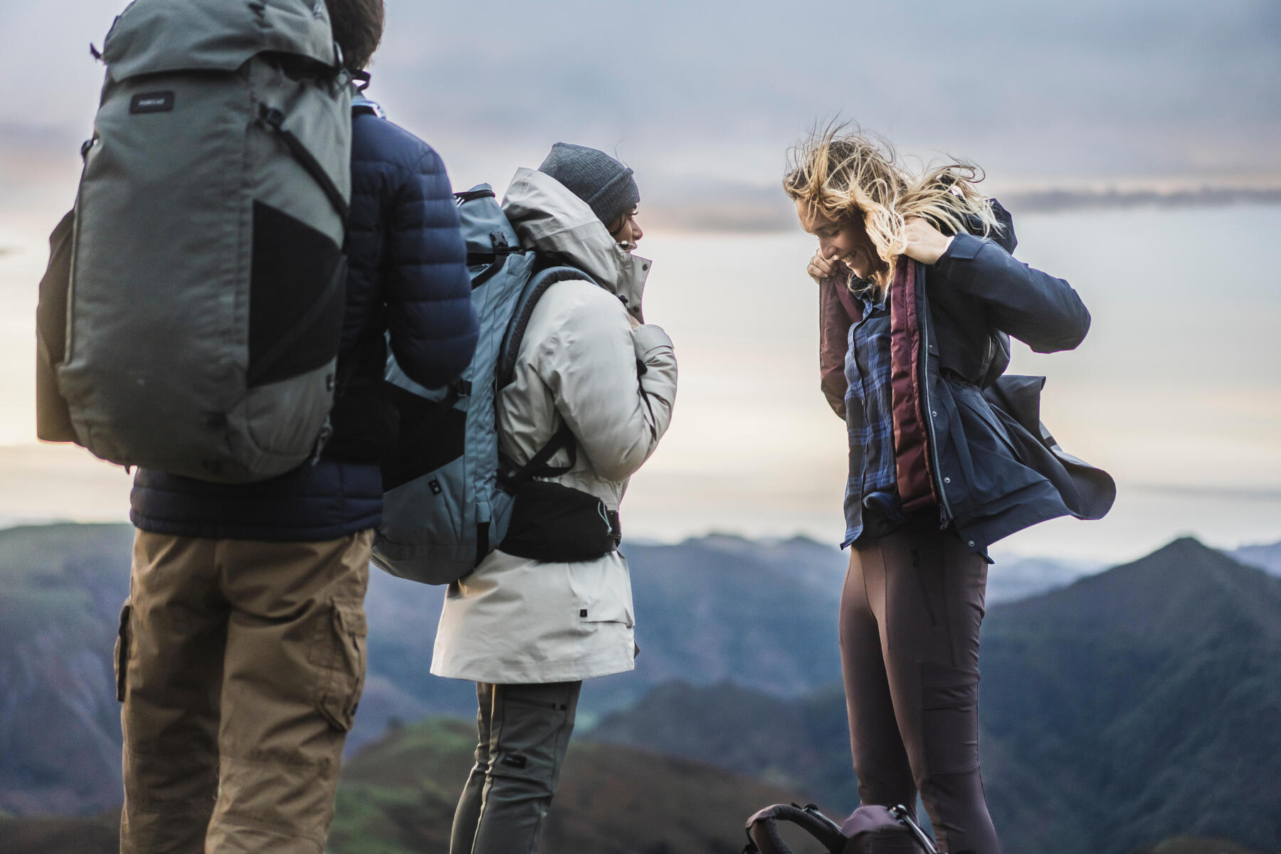 Kobiety i mężczyzna w odzieży outdoorowej z plecakami w górach