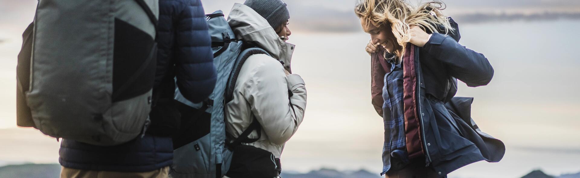 kobiety i mężczyzna w odzieży outdoorowej z plecakami w górach