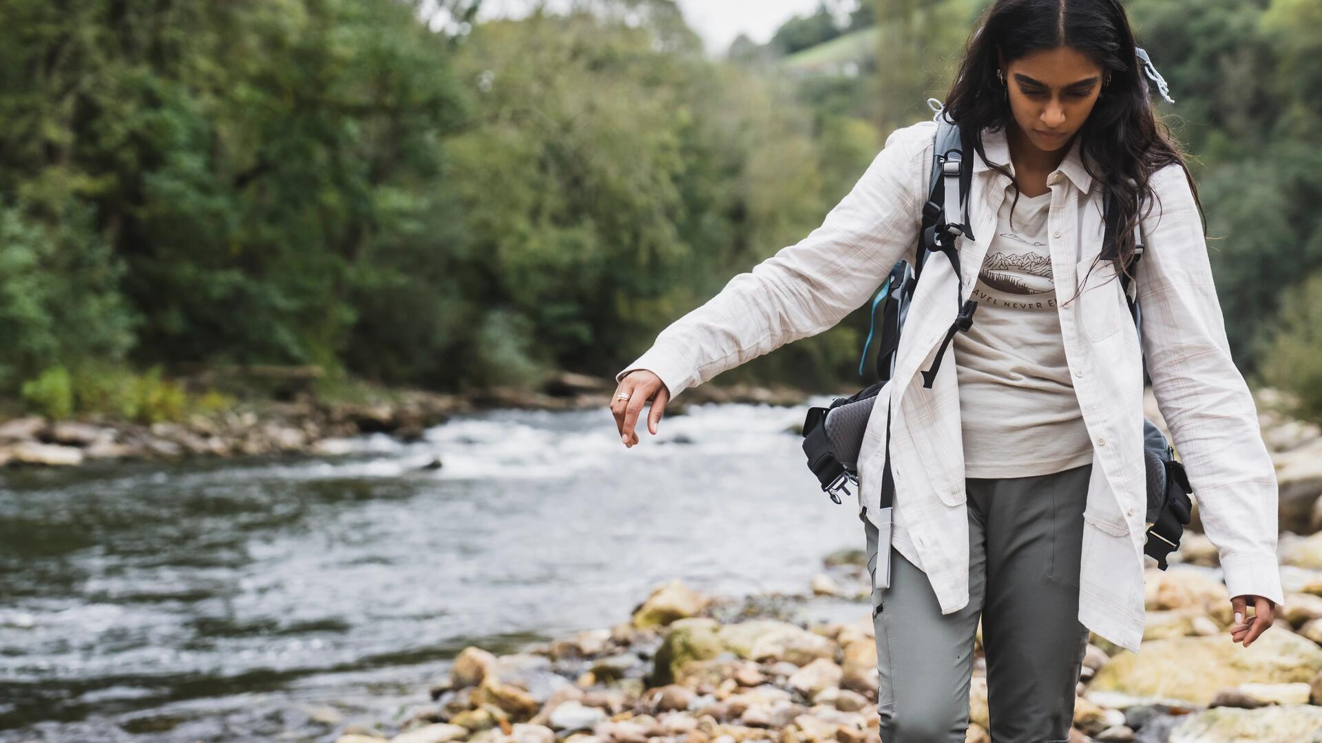 kobieta idąca wzdłuż rzeki w odzieży outdoorowej