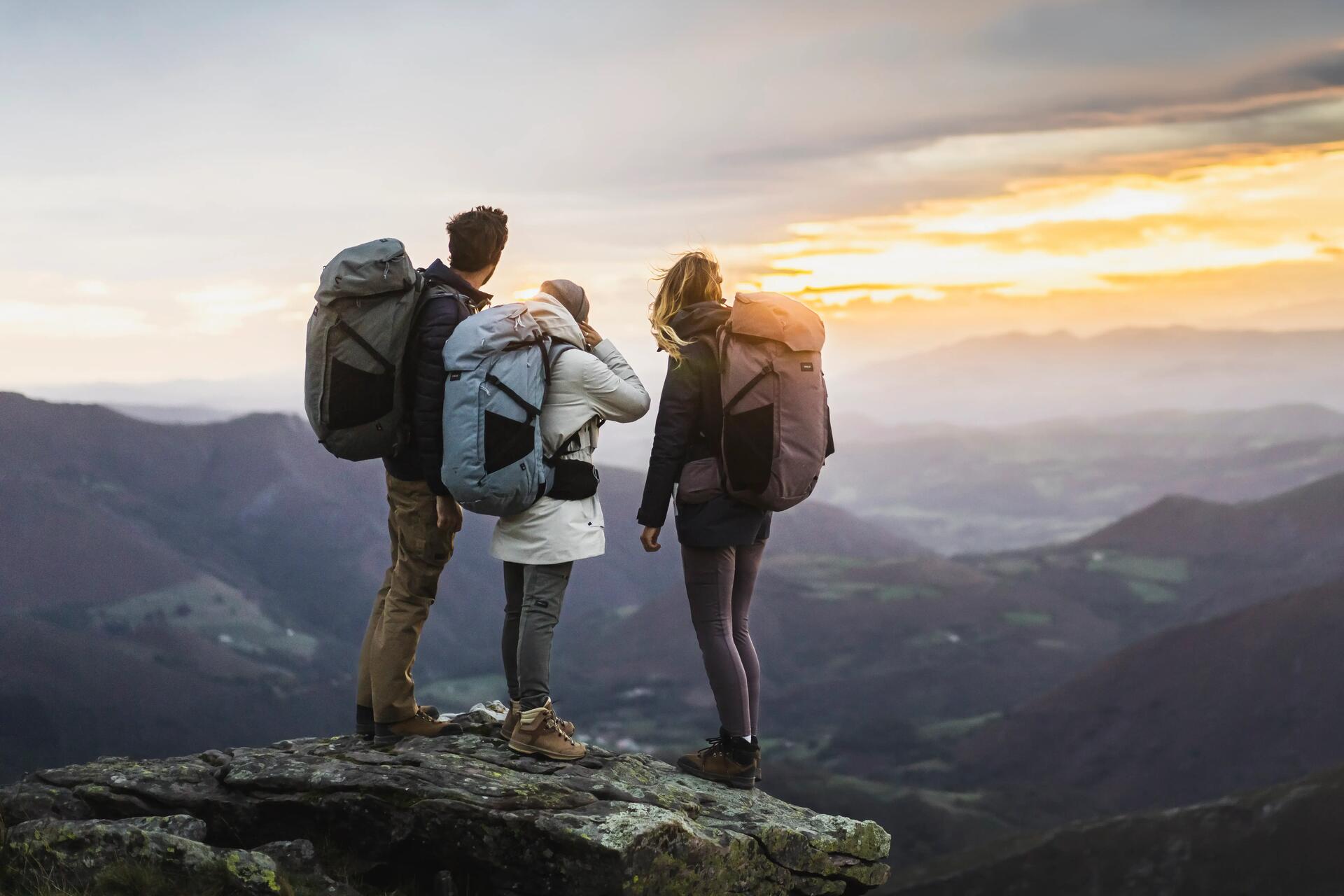 3 Personen mit Rucksack blicken in den Horizont