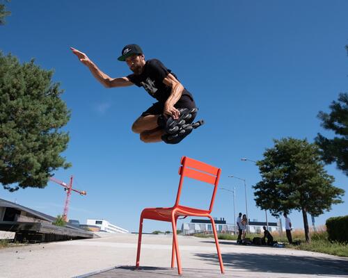 Guy with inline skates jumping over something with a blue sky background