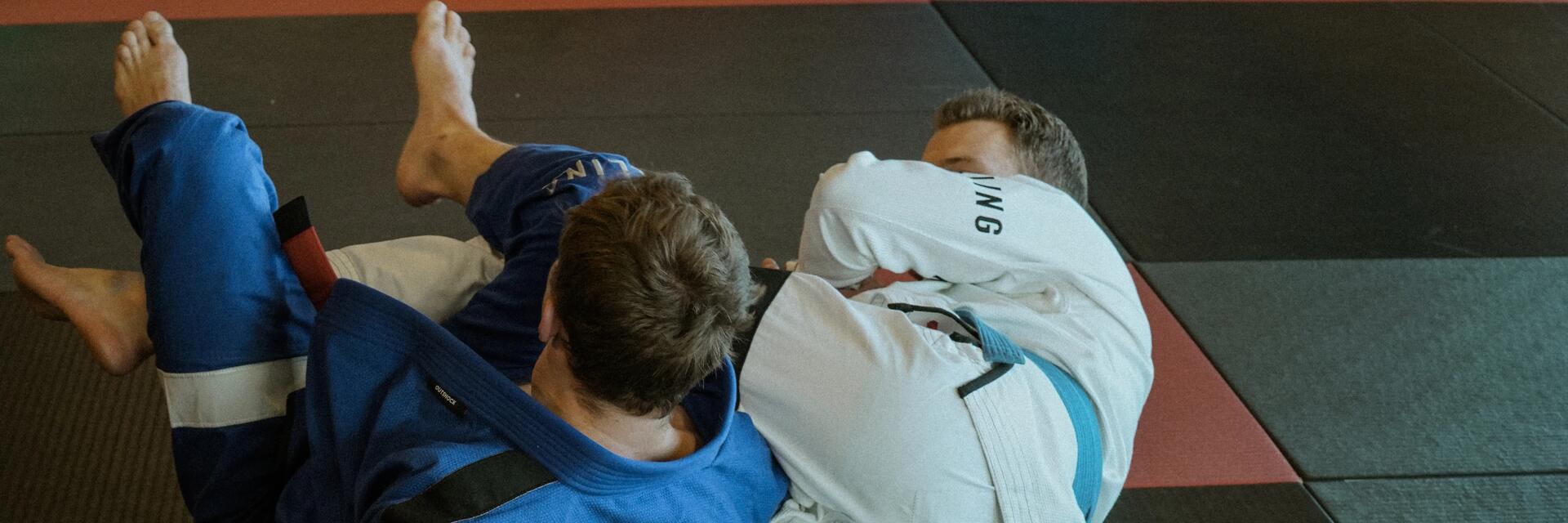 Mężczyźni z pasami BJJ walczący na macie