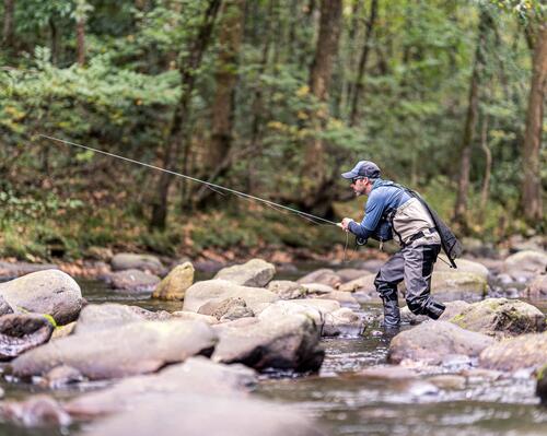 man fishing on rocks on  a river