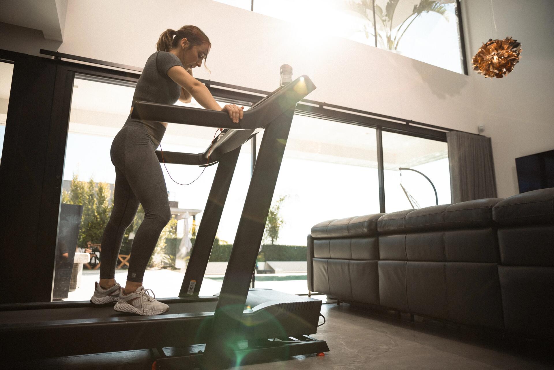 Kobieta w odzieży fitness wykonująca trening interwałowy na bieżni w celu uzyskania efektu chudnięcia