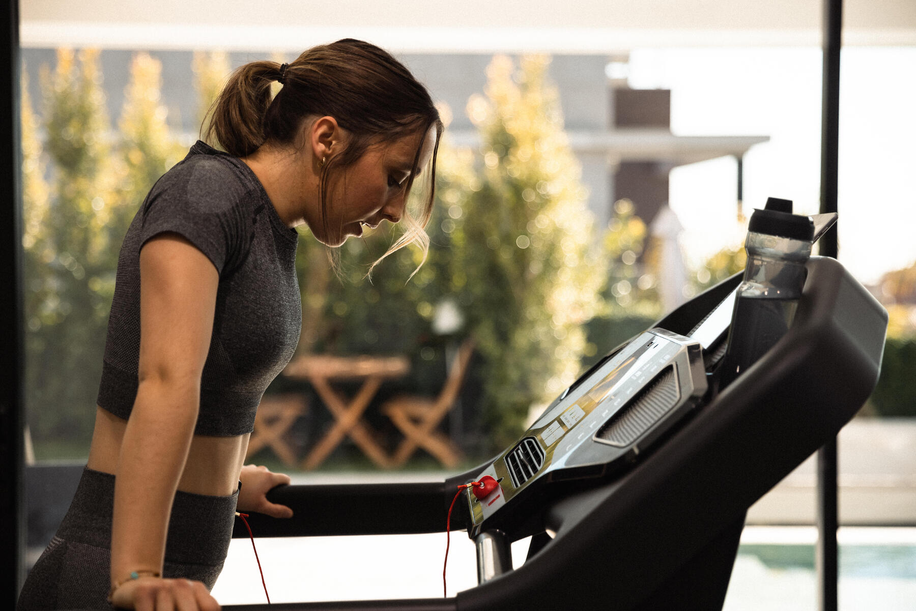 Kobieta w stroju fitness robiąca sobie przerwę podczas treningu biegowego na bieżni elektrycznej
