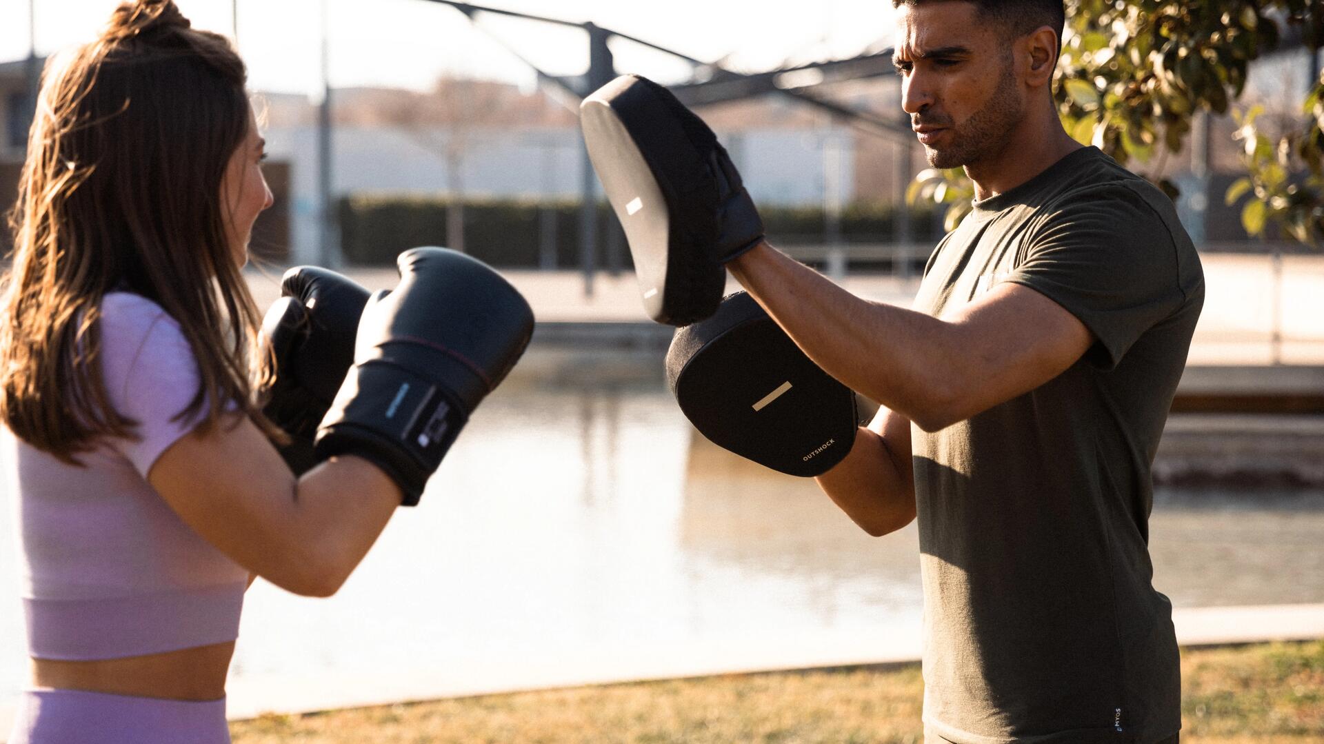 kobieta w rękawicach bokserskich trenująca z mężczyzną z tarczami bokserskimi na rękach