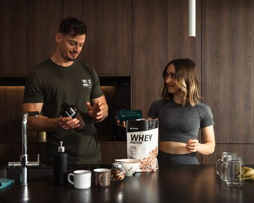 Wysportowany mężczyzna i kobieta przygotowują potrawę z odżywką białkową