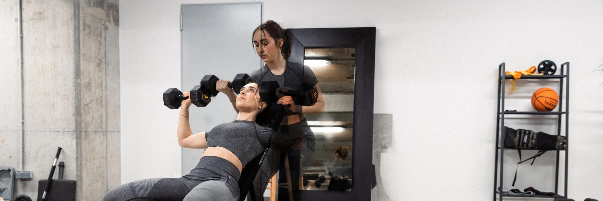 kobieta w odzieży fitness trenująca z hantlami na ławce skośnej do ćwiczeń