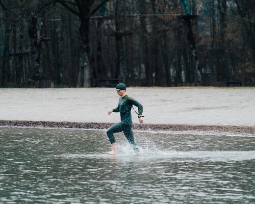 Mężczyzna w piance czepku i okularach wchodzący do wody