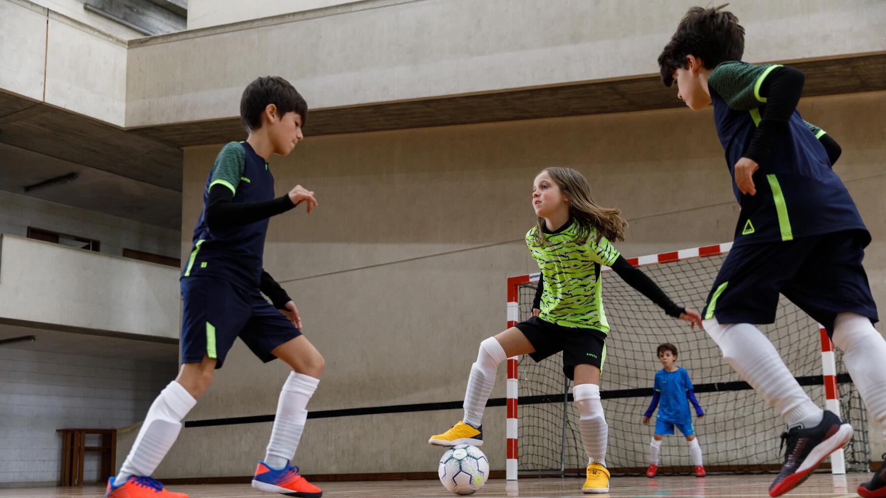 Kinder spielen Fußball in der Halle.