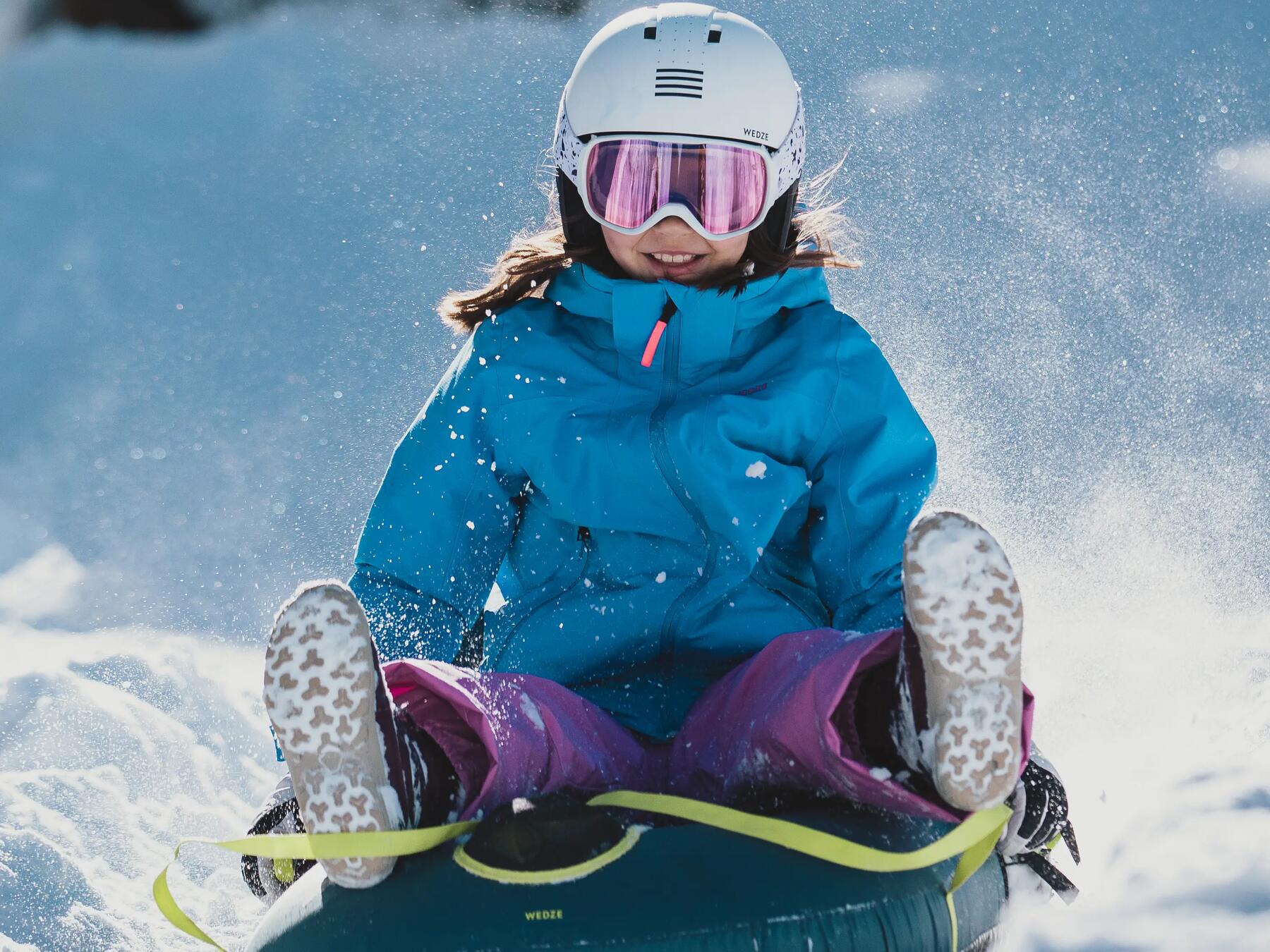 Dziewczynka uprawiająca aktywność fizyczną na śniegu zjeżdżając na sankach