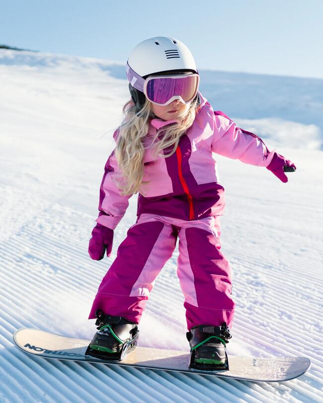 Mächen fährt Snowboard im rosa Skianzug