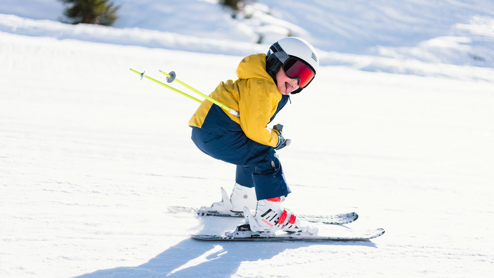 chłopiec w goglach i kasku narciarskim zjeżdżający na nartach ze stoku 