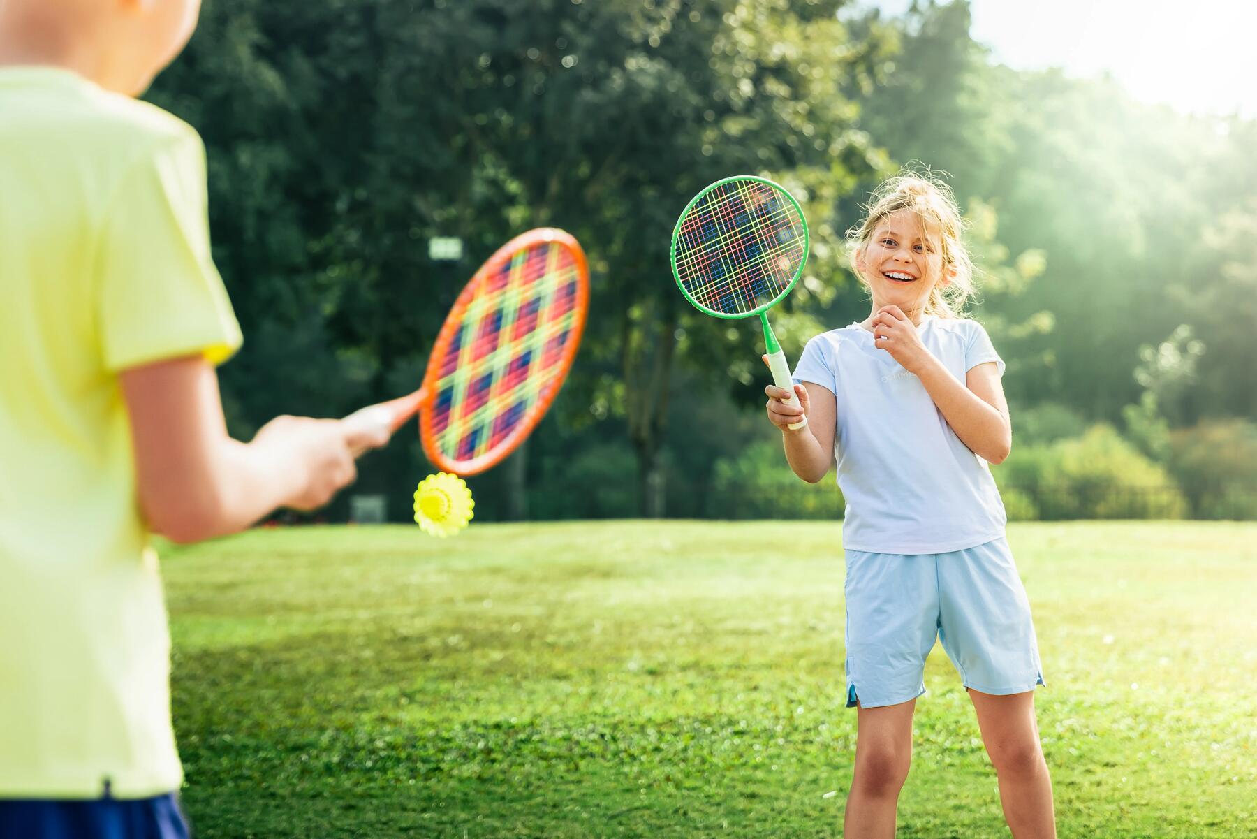 Dzieci w strojach sportowych grające w kometkę używając lotkę i rakietki do badmintona