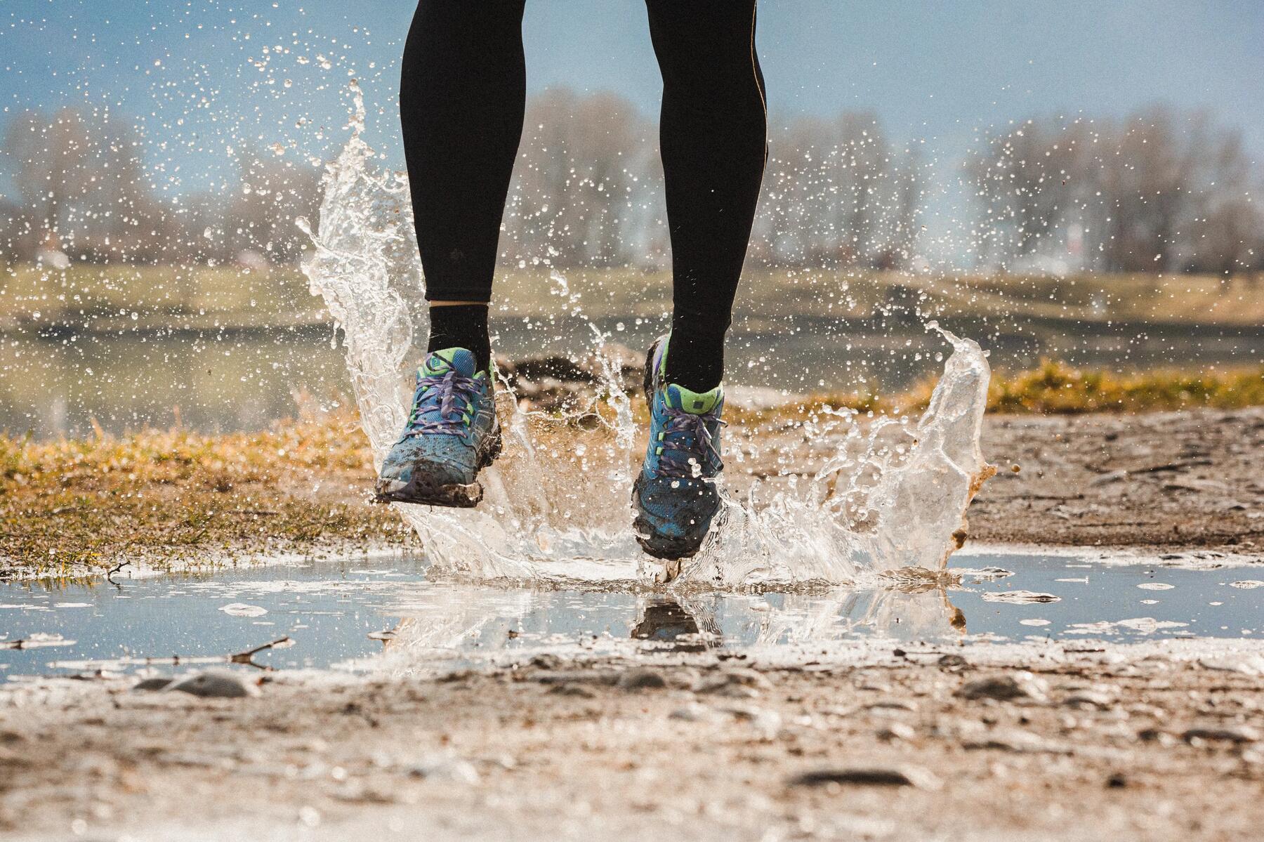 Kobieta biegnąca przez kałuże biorąca udział w utlra trail maratonie