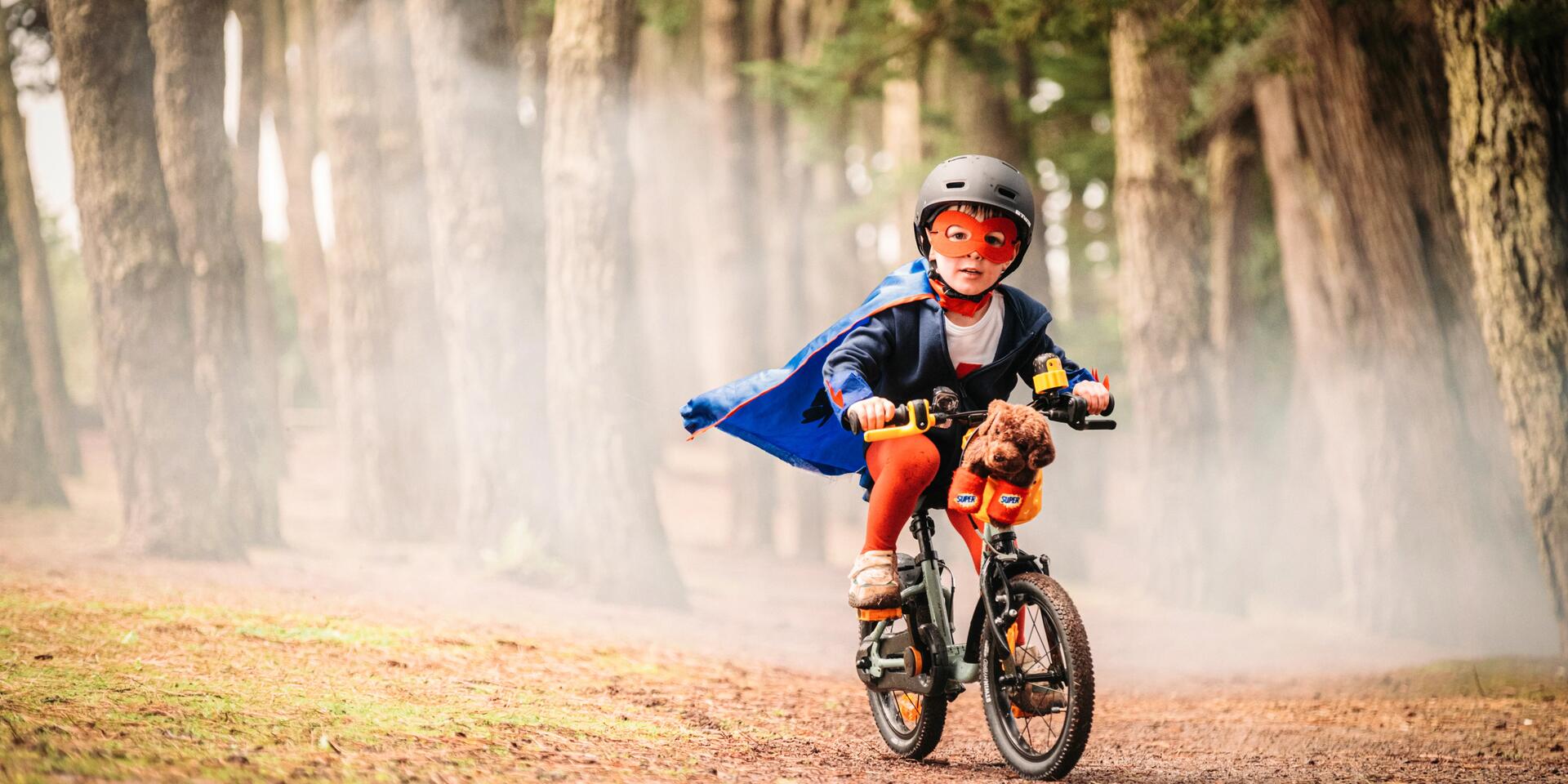 chłopiec w kasku rowerowym jadący na rowerku dziecięcym 