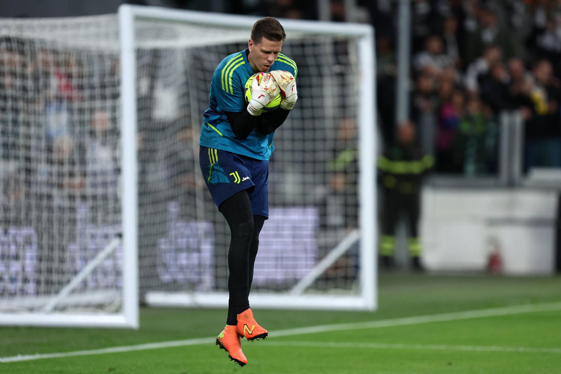 Wojciech Szczęsny w rękawicach bramkarskich trzymający piłkę do piłki nożnej stojąc na pozycji bramkarza