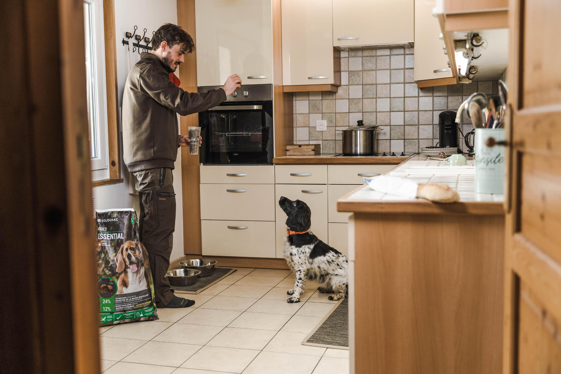 Mężczyzna trzymający przysmak dla psa w ręku obok pies czekający na smakołyk