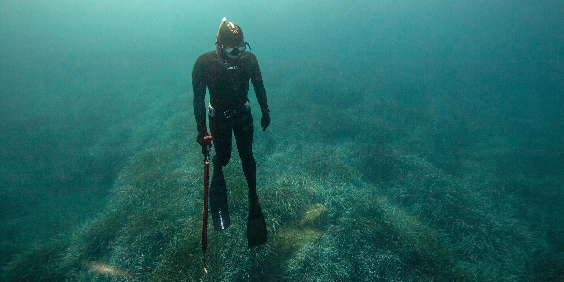 nurek w kombinezonie i masce do freedivingu nurkujący w głębinach