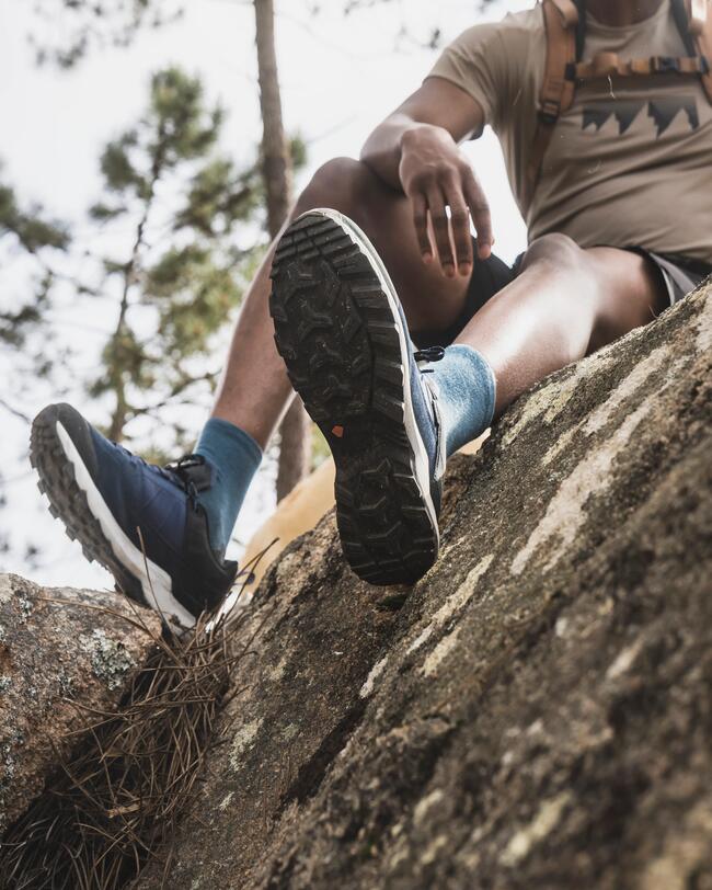 Mann sitzt bei einer Wanderung auf einem Baumstamm
