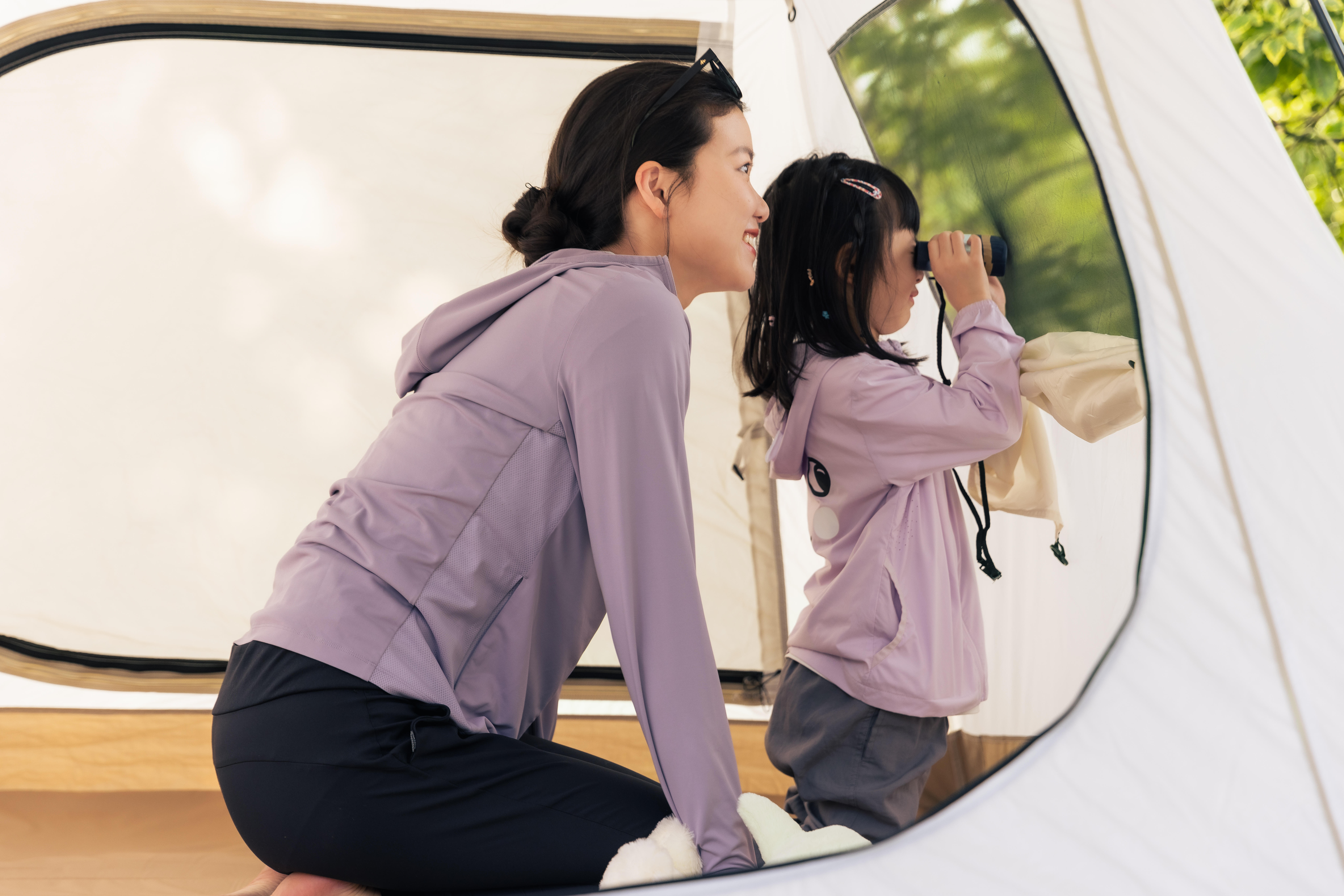 Child using binoculars inside a family camping tent
