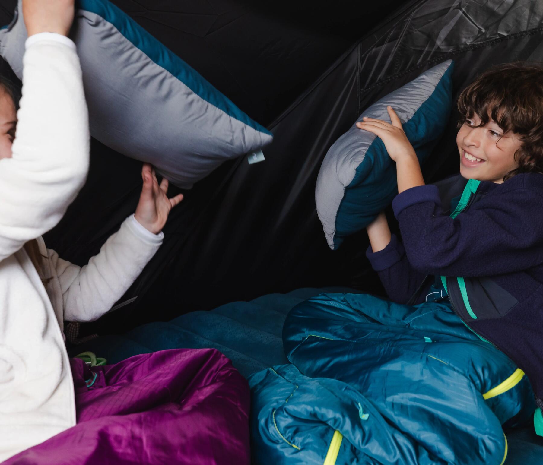 2 dzieci z poduszkami i śpiworami w namiocie