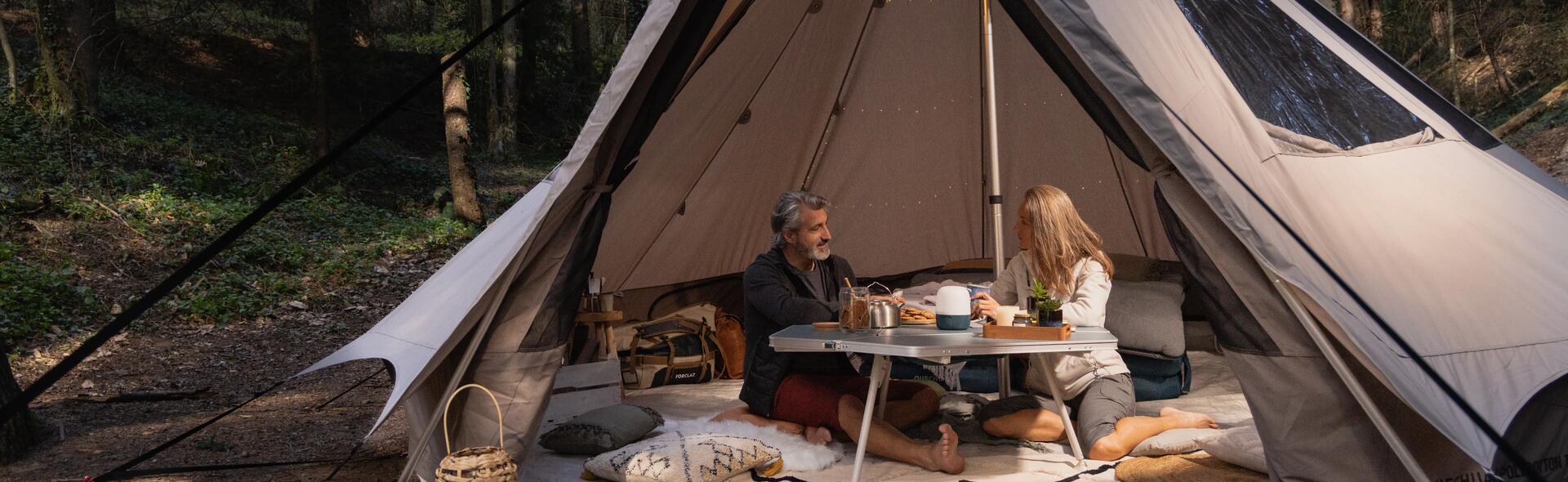 kobieta i mężczyzna siedzący przy stoliku turystycznym w namiocie z  jedzeniem