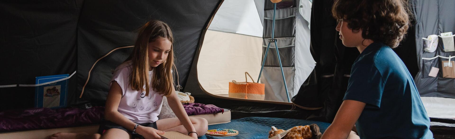 chłopiec i dziewczynka bawiący się w namiocie turystycznym 
