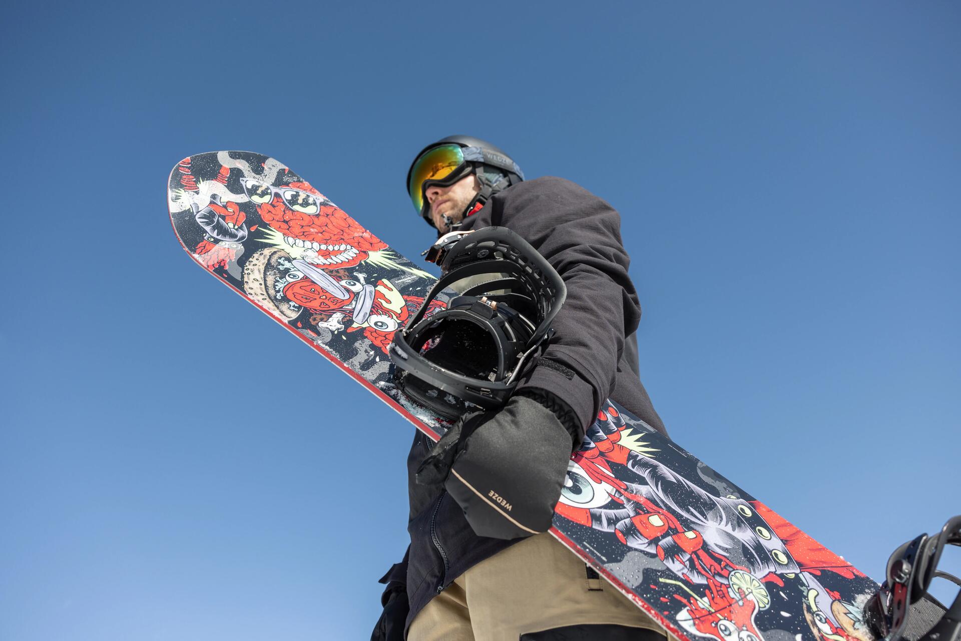 Mężczyzna trzymający deskę snowboardową w rękawiczkach