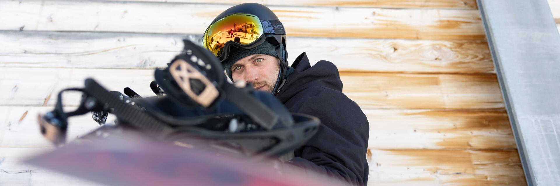 Snowboardzista trzymający deskę w goglach